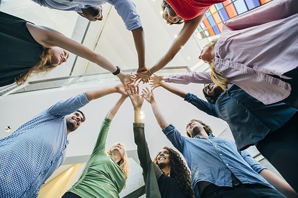 Happy coworkers doing group cheer and handshake